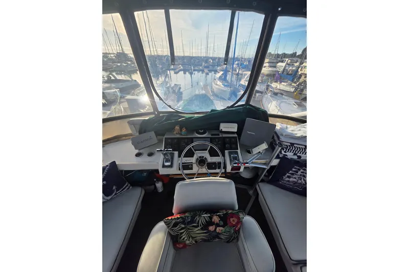 Slide: The Image of 1989 Bayliner 3888 Motoryacht helm with marina view, featuring navigation equipment and seating. - 32