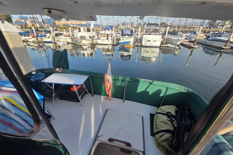 Slide: The Image of 1989 Bayliner 3888 Motoryacht docked at marina, view from deck with table and flag. - 35