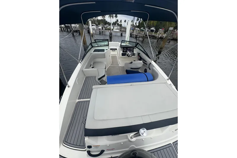 Slide: The Image of 2022 Sea Ray 19 SPX OB boat interior with seating and steering wheel, docked by the water. - 12