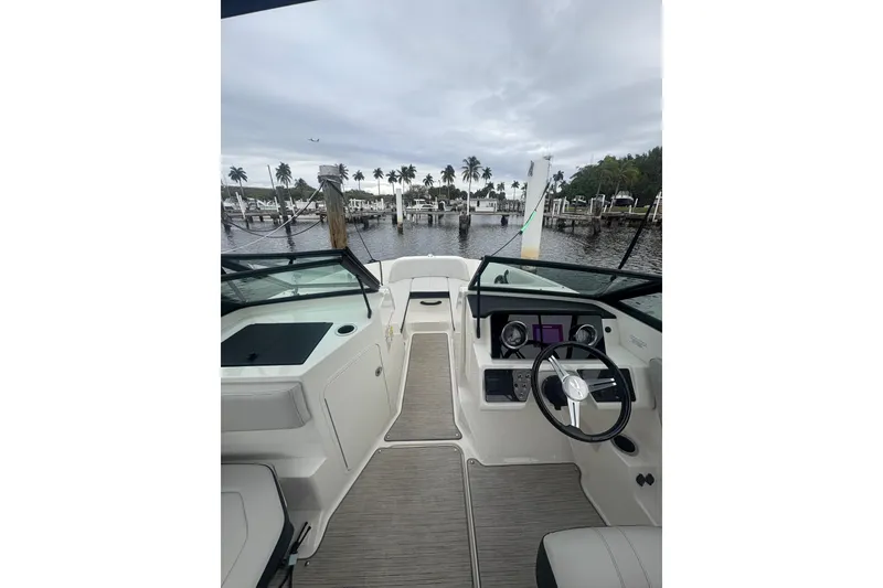 Slide: The Image of 2022 Sea Ray 19 SPX OB boat interior with steering wheel, docked near palm trees. - 18