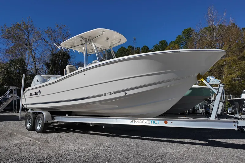 Slide: The Image of 2025 Bulls Bay 255 CC boat on trailer, parked outdoors under clear blue sky. - 0