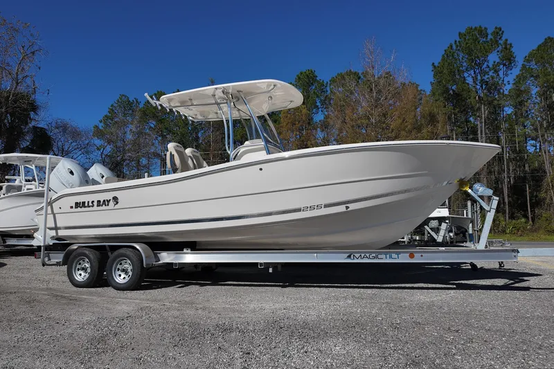Slide: The Image of 2025 Bulls Bay 255 CC boat on trailer, parked outdoors under clear blue sky. - 2