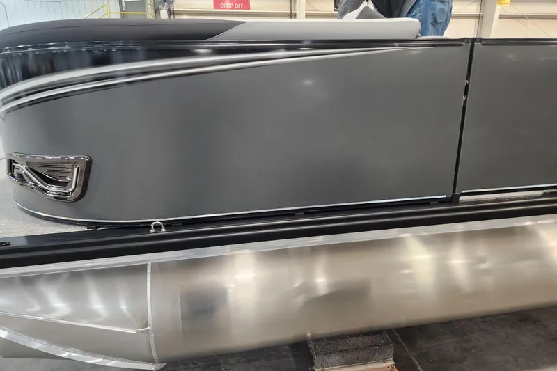 Slide: The Image of 2026 Tahoe Pontoon 23 LTZ Quad Lounge with outboard motor and ladder, parked outdoors. - 11