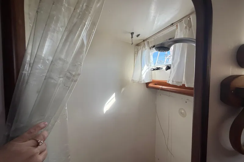 Slide: The Image of Small boat shower area with curtain, window, and showerhead in a 1999 Passport 456. - 18