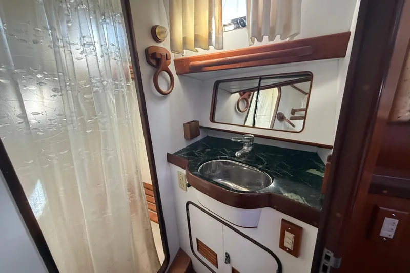 Slide: The Image of Compact bathroom with green marble sink, mirror, and shower curtain in a 1999 Passport 456. - 20