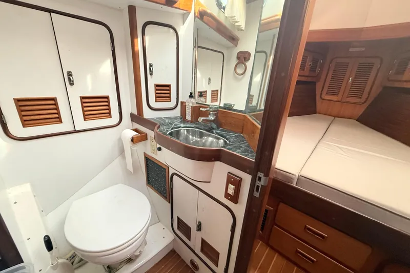 Slide: The Image of Compact boat bathroom with sink, toilet, and adjacent sleeping area in a 1999 Passport 456. - 29