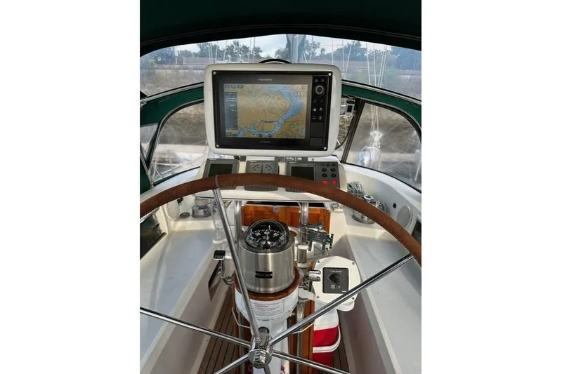 Slide: The Image of Sailboat cockpit with navigation equipment, featuring a steering wheel and compass, Passport 456, 1999. - 35