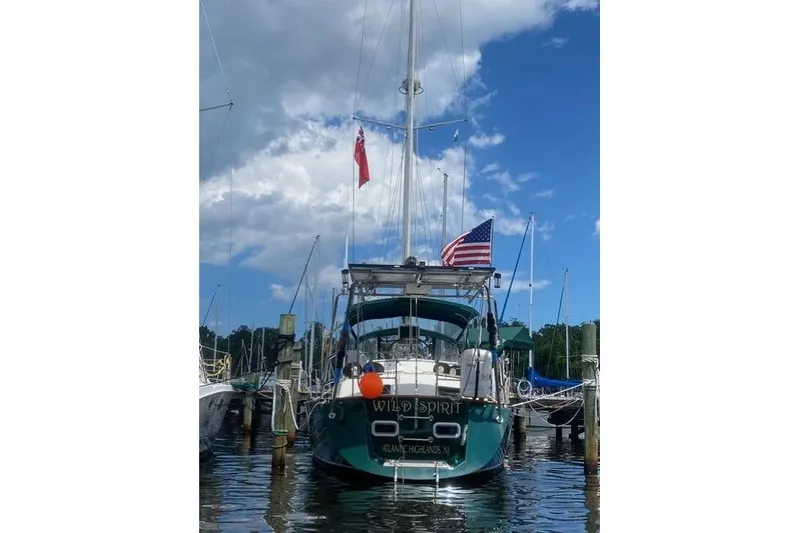 Slide: The Image of Sailboat "Wild Spirit" docked, displaying American and red flags, under a partly cloudy sky. - 43
