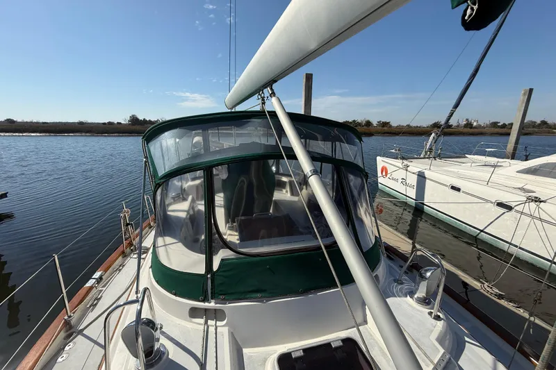 Slide: The Image of Sailboat docked on calm water, featuring a green canopy, Passport 456, 1999 model. - 54