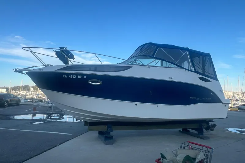 The Image of 2008 Bayliner 245 Cruiser boat on a dock, blue and white exterior. - 0