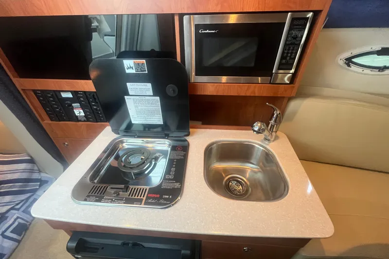 Slide: The Image of 2008 Bayliner 245 Cruiser kitchen with stove, sink, and microwave. - 7