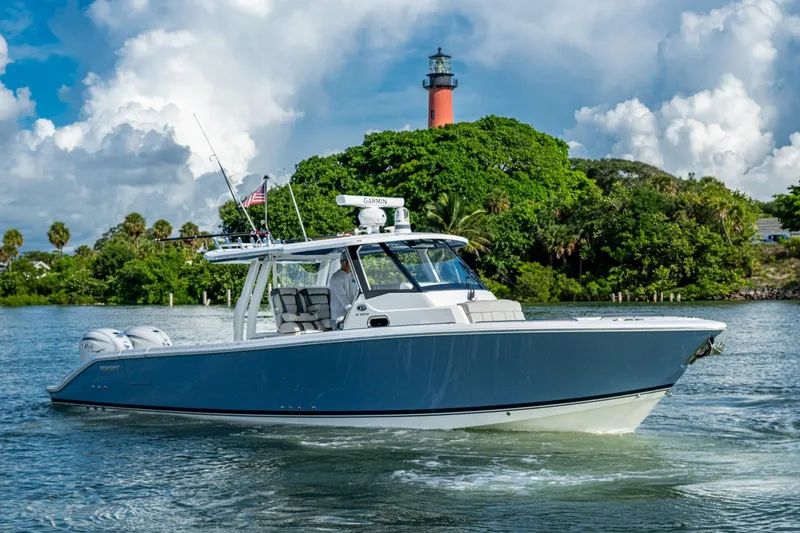 The Image of 2023 Pursuit S 358 Sport boat cruising near a lush island and lighthouse. - 0