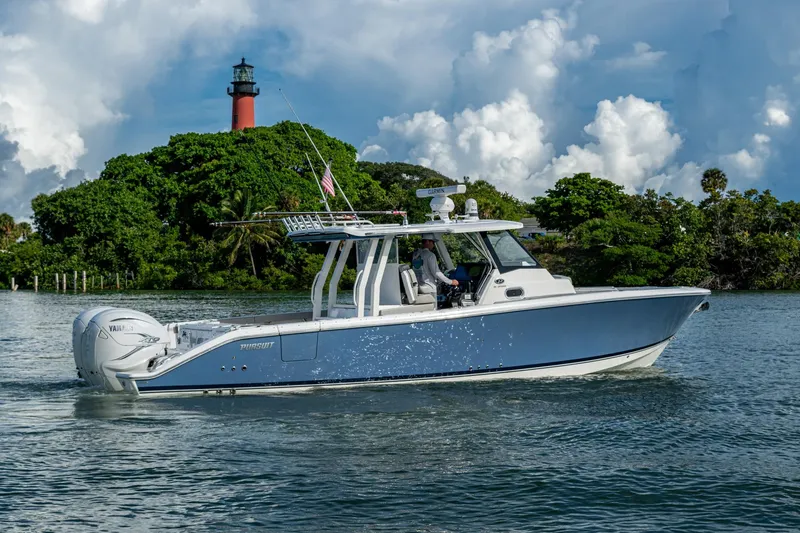 Slide: The Image of 2023 Pursuit S 358 Sport boat cruising near a lush island with a lighthouse. - 10