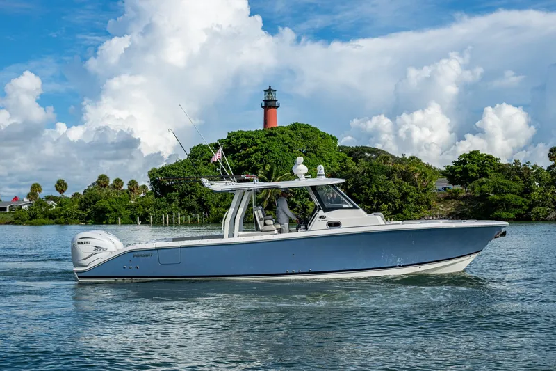 Slide: The Image of 2023 Pursuit S 358 Sport boat cruising near lush island and lighthouse. - 11