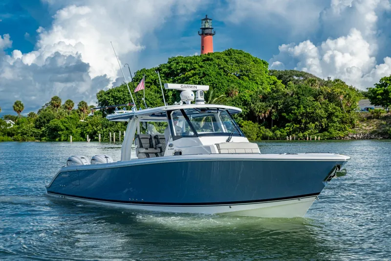 Slide: The Image of 2023 Pursuit S 358 Sport boat cruising near a lush island with a lighthouse. - 12