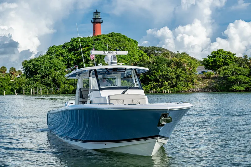 Slide: The Image of 2023 Pursuit S 358 Sport boat cruising near a lush island with a lighthouse. - 13