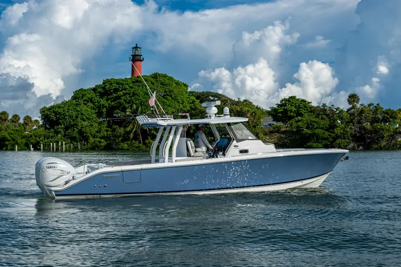 Slide: The Image of 2023 Pursuit S 358 Sport boat cruising near a lighthouse with lush greenery. - 14