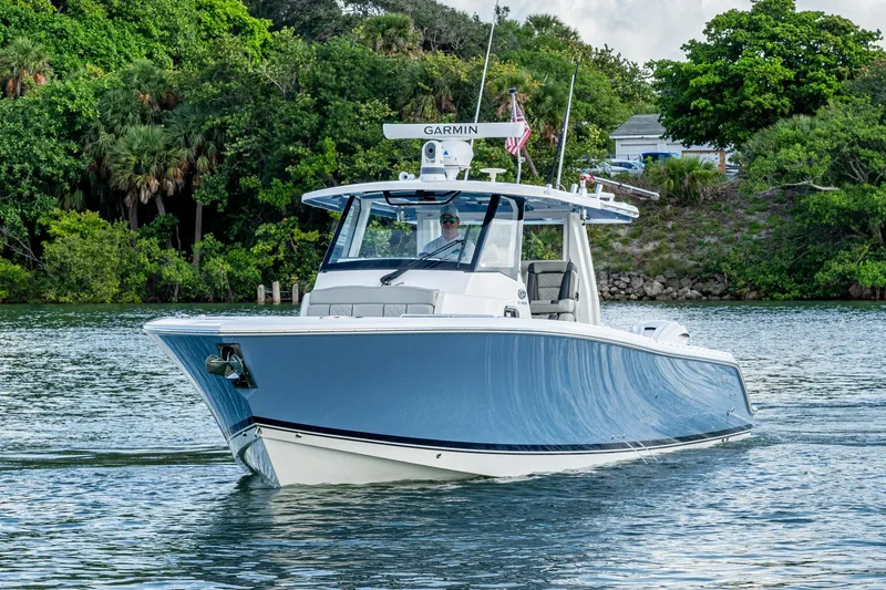 Slide: The Image of 2023 Pursuit S 358 Sport boat cruising on a scenic waterway. - 2