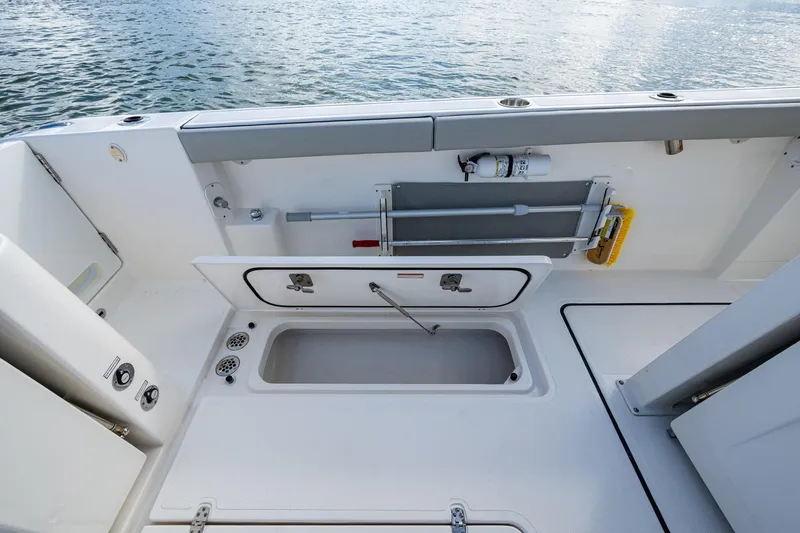 Slide: The Image of 2023 Pursuit S 358 Sport boat deck with storage compartments and cleaning tools. - 20