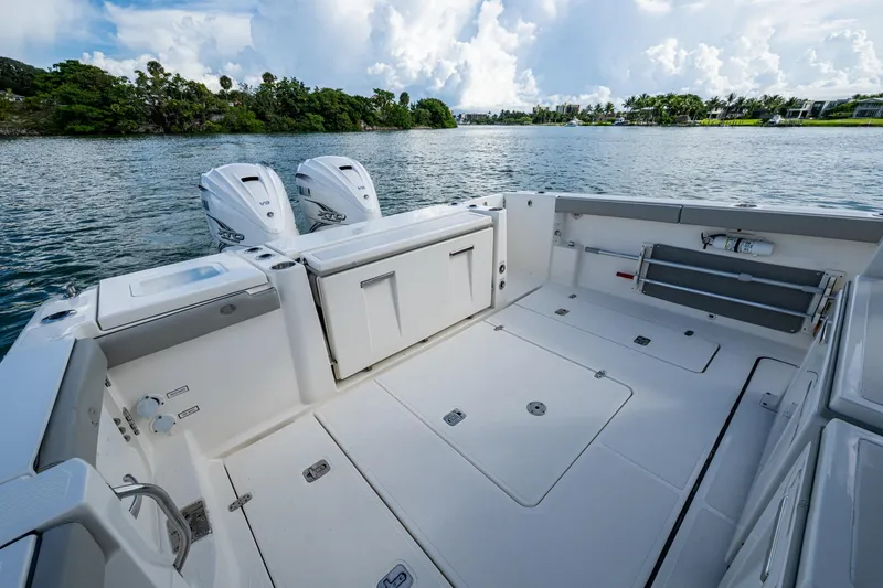Slide: The Image of 2023 Pursuit S 358 Sport boat deck with dual engines on a scenic waterway. - 22