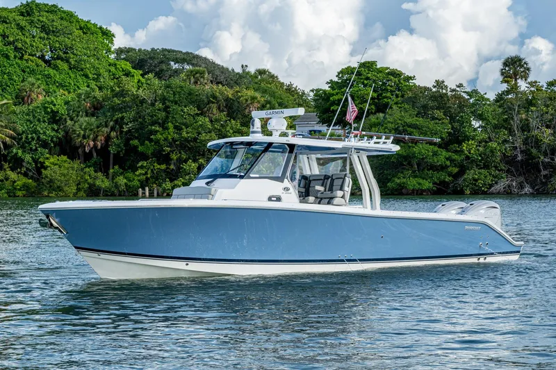 Slide: The Image of 2023 Pursuit S 358 Sport boat on water, surrounded by lush greenery. - 3