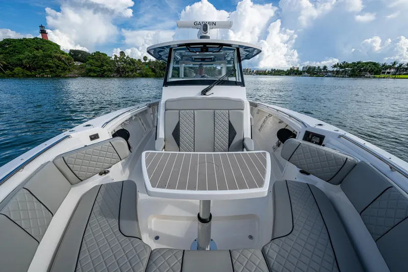 Slide: The Image of 2023 Pursuit S 358 Sport boat interior with luxurious seating and table on a scenic lake. - 37