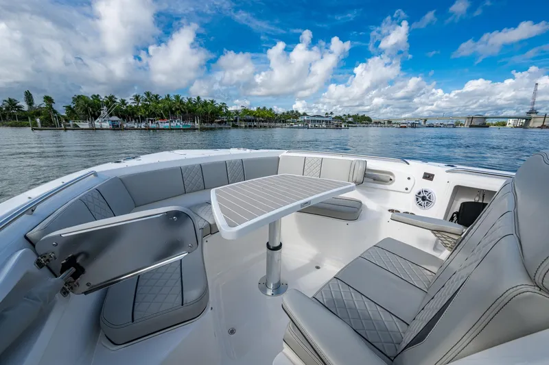 Slide: The Image of 2023 Pursuit S 358 Sport boat interior with seating and table, on a scenic waterway. - 38