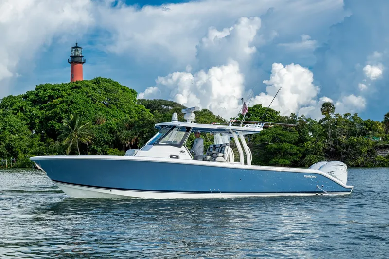 Slide: The Image of 2023 Pursuit S 358 Sport boat on water near lush greenery and lighthouse. - 4