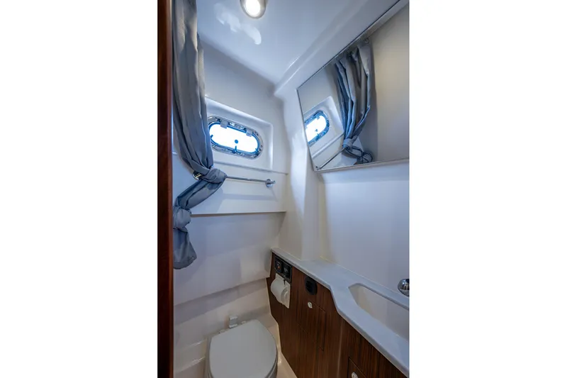 Slide: The Image of 2023 Pursuit S 358 Sport boat bathroom with window, mirror, and wooden cabinetry. - 42