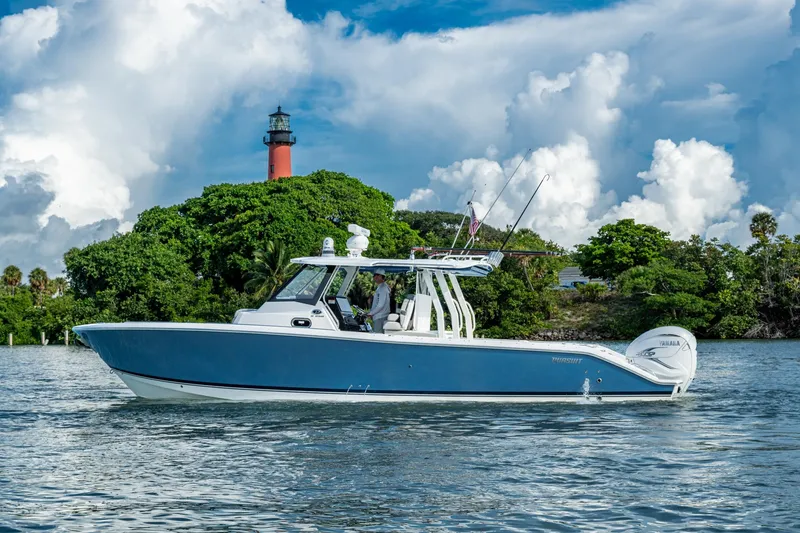 Slide: The Image of 2023 Pursuit S 358 Sport boat cruising near a lighthouse with lush greenery. - 5