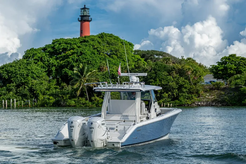 Slide: The Image of 2023 Pursuit S 358 Sport boat cruising near a lush island with a lighthouse. - 8