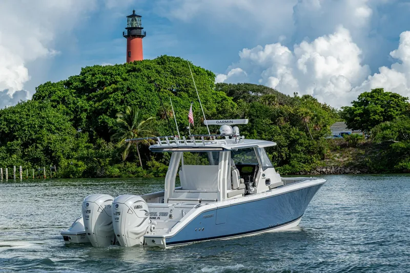 Slide: The Image of 2023 Pursuit S 358 Sport boat cruising near a lighthouse and lush greenery. - 9