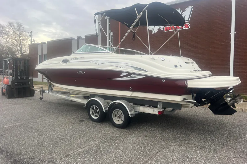 Slide: The Image of 2006 Sea Ray 240 Sundeck boat on trailer, parked outside a brick building. - 2