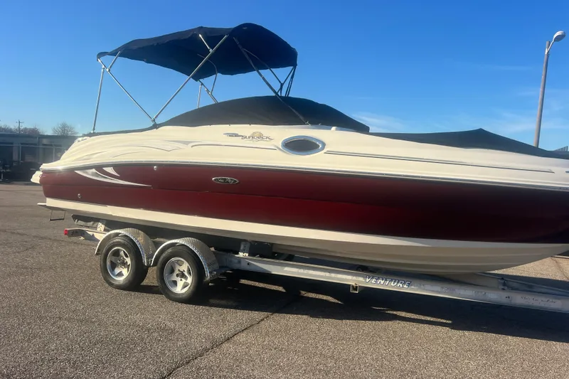 Slide: The Image of 2006 Sea Ray 240 Sundeck boat on trailer with canopy, parked on pavement. - 33