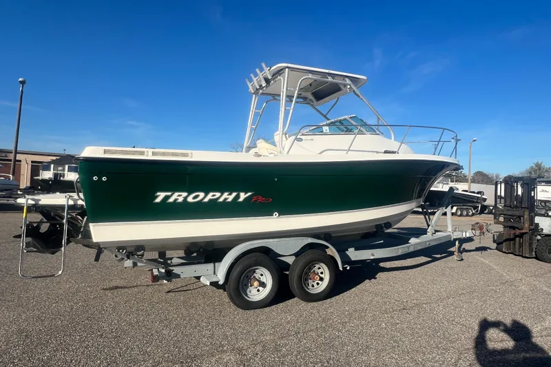 Slide: The Image of 2004 Trophy 2352 Walkaround boat on trailer, green hull, clear sky background. - 35