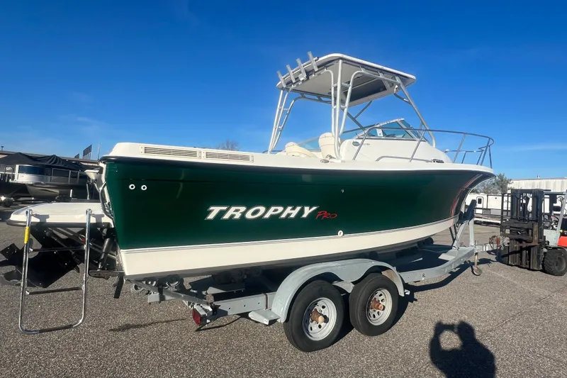 Slide: The Image of 2004 Trophy 2352 Walkaround boat on trailer, green hull, clear sky background. - 36