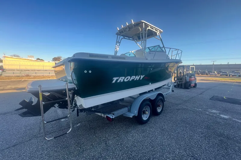 Slide: The Image of 2004 Trophy 2352 Walkaround boat on trailer in parking lot, clear sky background. - 7