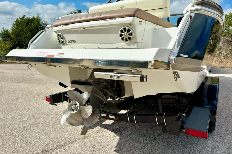 Slide: The Image of 2011 Cobalt 276 boat rear view with propeller and trailer, parked outdoors. - 14