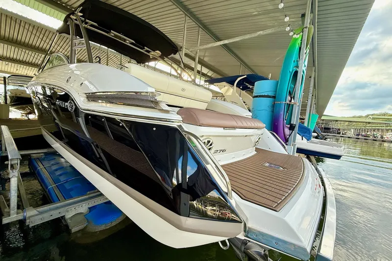 Slide: The Image of 2011 Cobalt 276 boat docked under a covered marina with paddleboards. - 18