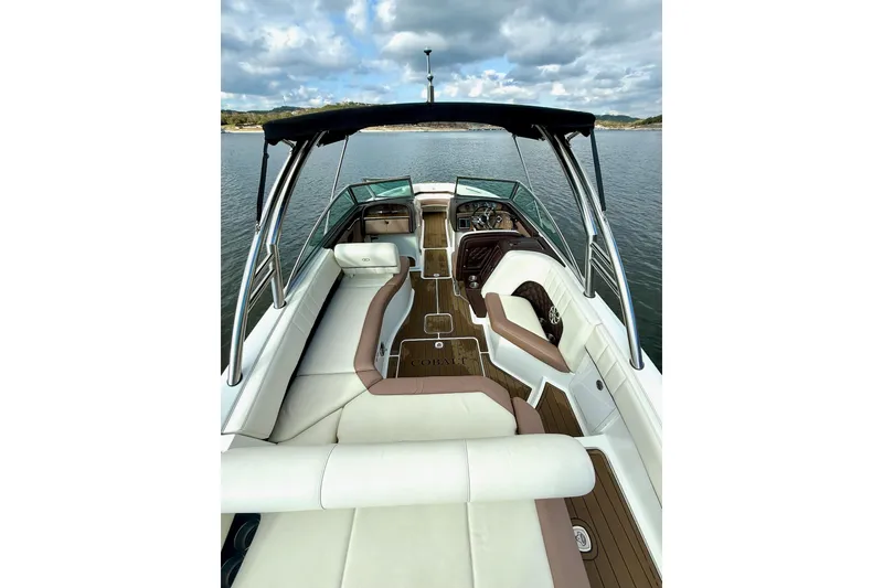 Slide: The Image of 2011 Cobalt 276 boat interior with white seating and wooden flooring on a calm lake. - 22
