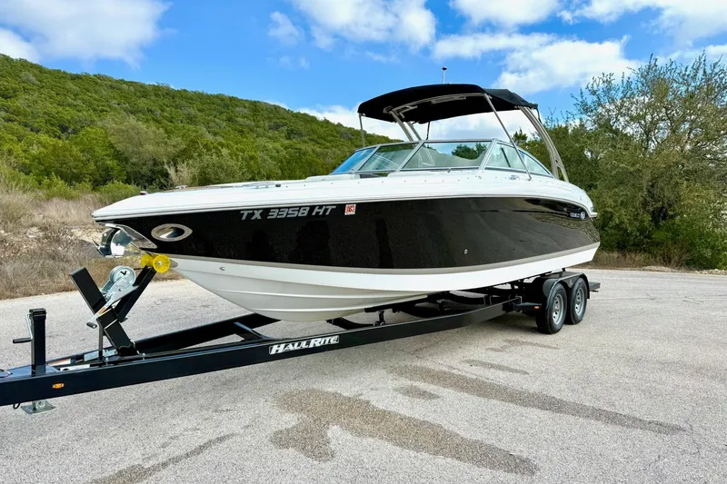 Slide: The Image of 2011 Cobalt 276 boat on trailer, parked outdoors with scenic background. - 9