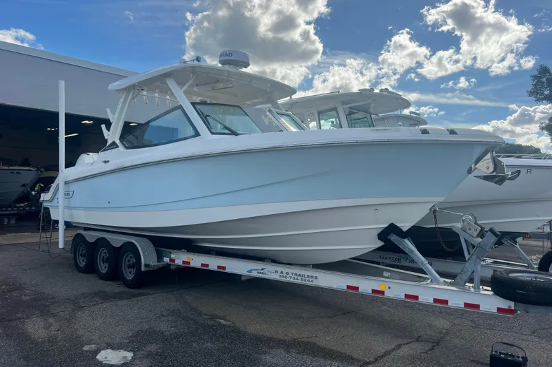 Slide: The Image of 2023 Boston Whaler 280 Vantage boat on a trailer under a cloudy sky. - 20