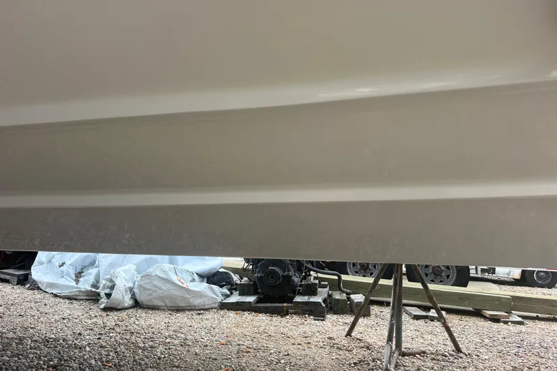 Slide: The Image of 2023 Boston Whaler 280 Vantage boat hull on stands, gravel ground. - 59