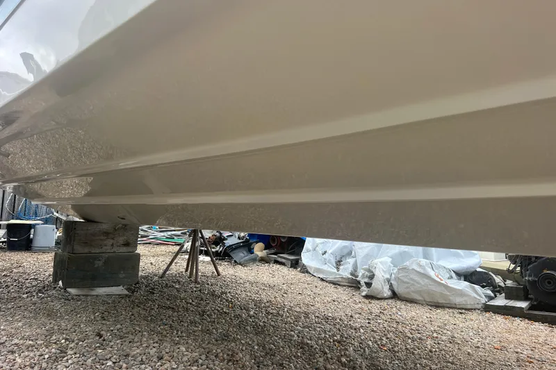 Slide: The Image of 2023 Boston Whaler 280 Vantage boat hull on gravel, supported by wooden blocks. - 60