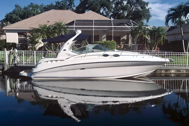 The Image of 2006 Sea Ray Sundancer 320 yacht docked by a waterfront home, reflecting on calm water. - 0
