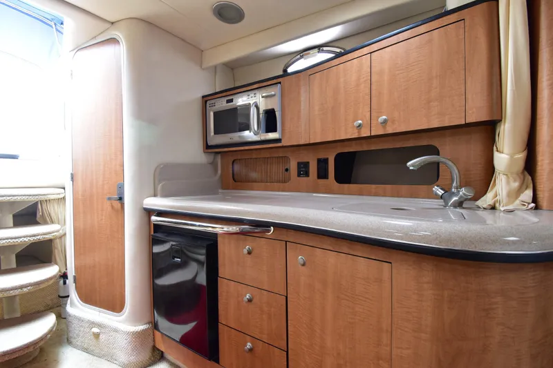 Slide: The Image of 2006 Sea Ray 320 Sundancer interior kitchen with wood cabinets and modern appliances. - 16