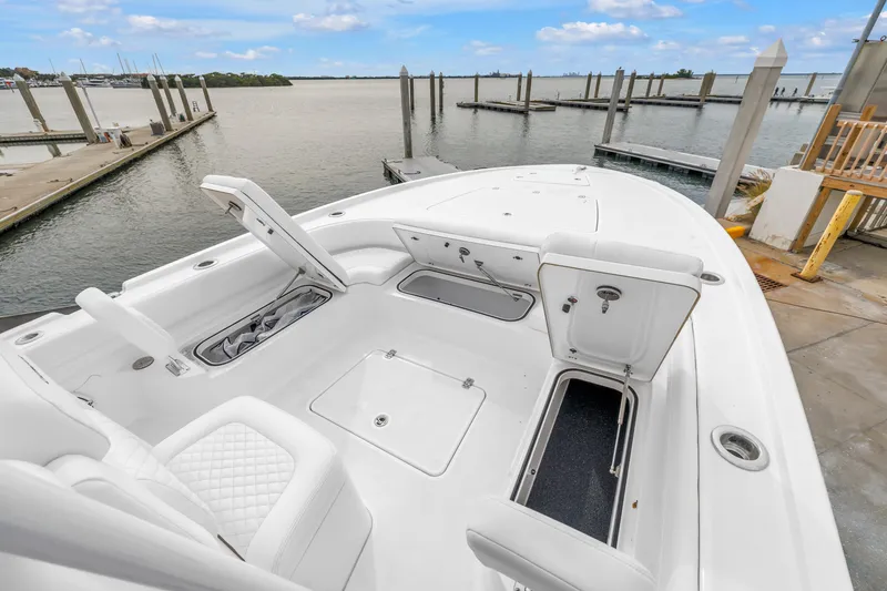 Slide: The Image of 2025 Caymas 28 HB boat with open storage compartments at a marina dock. - 21
