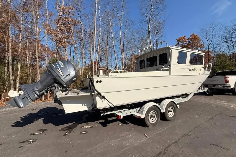 Slide: The Image of 2004 Boulton Explorer 24 boat on trailer, parked outdoors with trees in background. - 3
