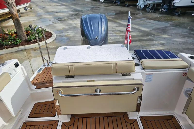 Slide: The Image of 2025 Ranger Tugs R-27 boat stern with seating, outboard motor, and American flag. - 10