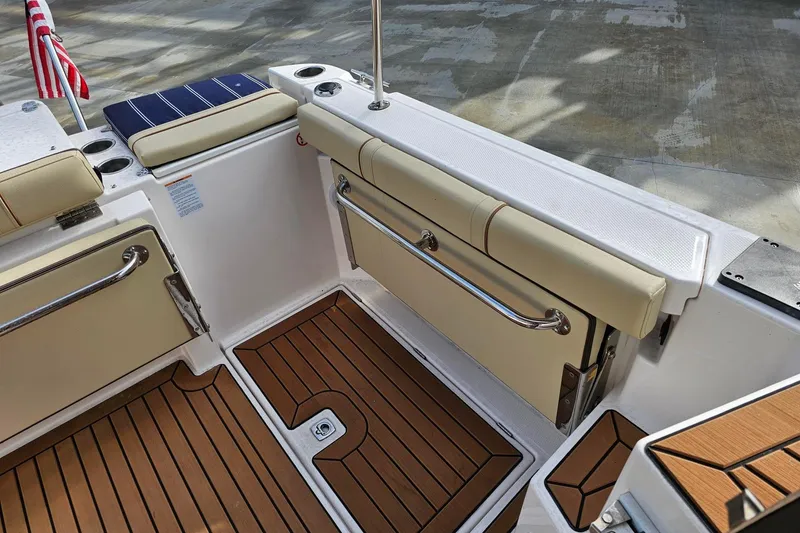Slide: The Image of 2025 Ranger Tugs R-27 boat interior with cushioned seating and wooden flooring. - 11